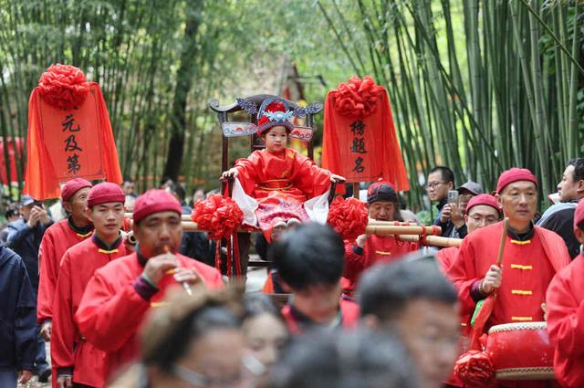 ↑ 5月3日，在山东省临沂市沂南县铜井镇竹泉村，游客参与体验高中“状元”表演。新华社发（王彦冰摄）