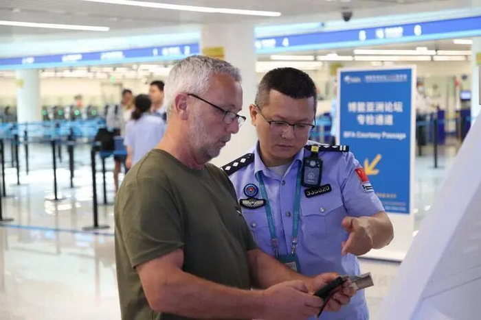 3月27日，海口美兰出入境边防检查站执勤民警指导入境旅客填写入境卡。新华社发（王羽摄）