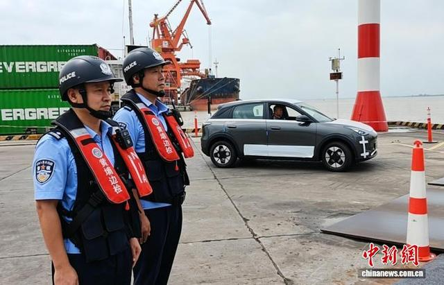 新沙港码头，黄埔边检站移民管理警察对装载出口国产新能源汽车的船舶进行监护。刘腾 摄