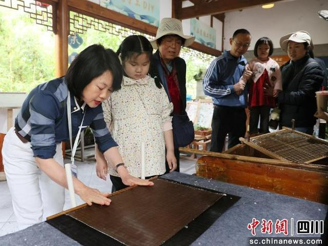柳江古镇游客孩童体验雅纸制作技艺。唐磊 摄