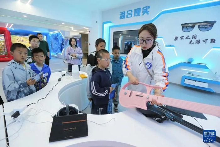 5月7日，甘肃省定西市安定区人工智能教育基地的工作人员向学生展示AI吉他。新华社发（王克贤 摄）