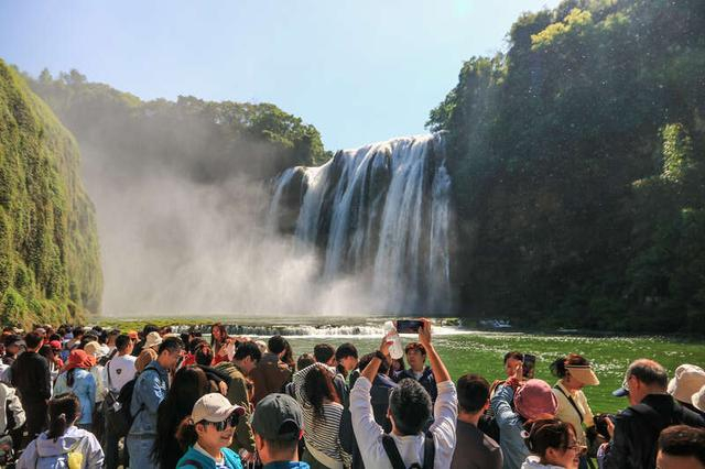 5月4日，贵州安顺，游客在黄果树瀑布游览拍照。“五一”假期黄果树景区迎来客流高峰，当日接待游客近5万人次。视觉中国供图