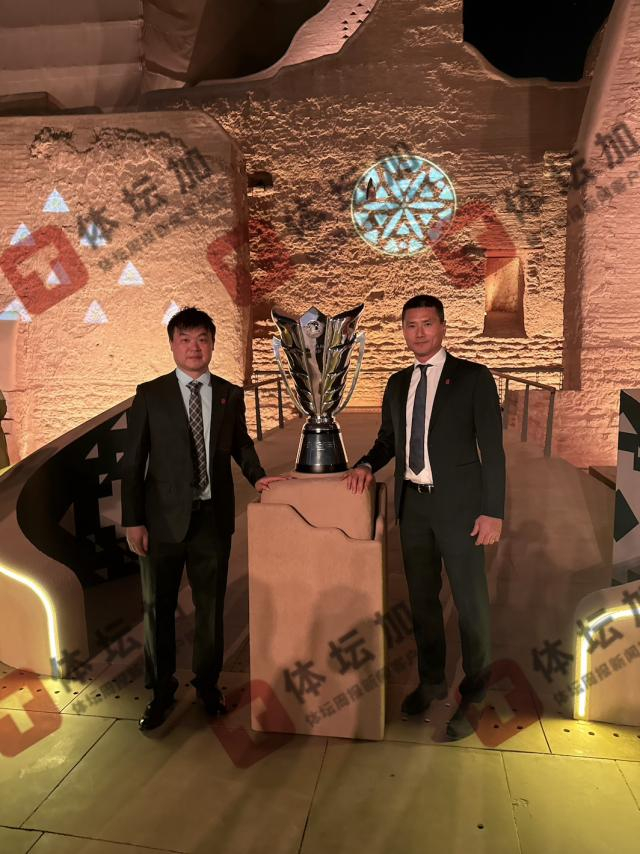 国管部副部长兼国家队领队童杰与主教练邵佳一在亚洲杯冠军奖杯前合影