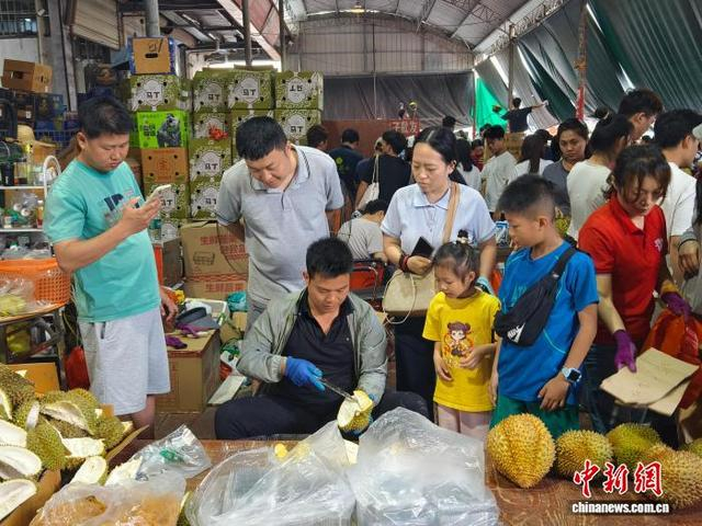 图为民众在等待商户帮开榴莲。刘芷邑 摄