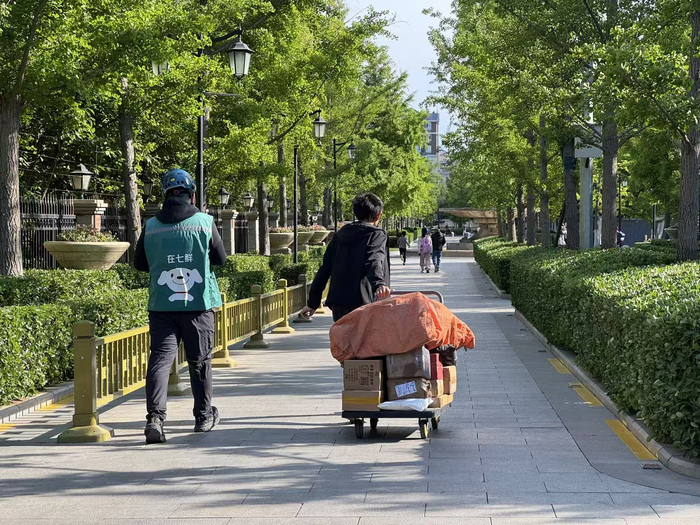 快递员小邓使用共享推车拉着一车快递货物进小区。新京报记者 耿子叶 摄