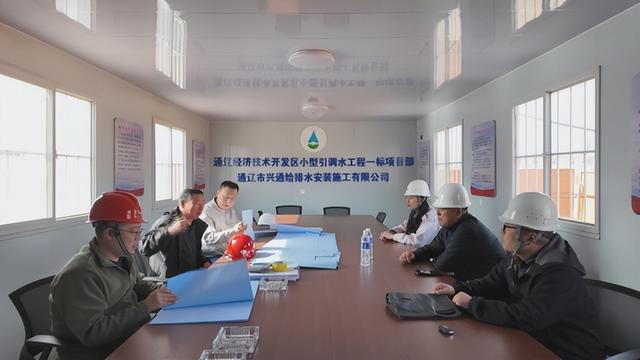 项目负责人与技术人员对照图纸研讨施工方案。山丹 摄
