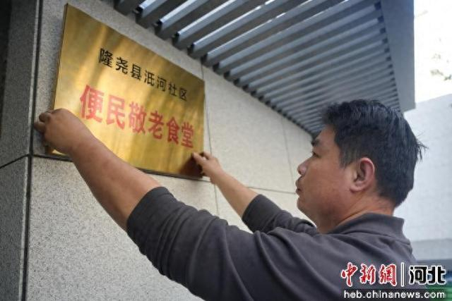图为河北省隆尧县天一府便民敬老食堂，工作人员正在挂牌。 张冬茹 摄