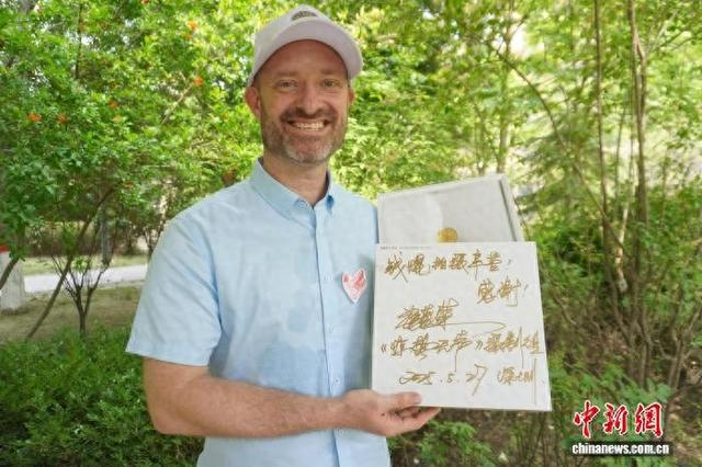 5月12日，河南郑州，美国演员钱焜展示中国导演张艺谋签名的丝巾礼盒。中新社记者 韩章云 摄