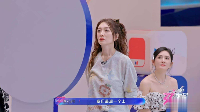  这一策略正是谢楠的妙计。她指示负责贴牌的徐梦洁分散放置牌子，目的是分散对手注意力。其他团队本想集中占最大区域来确保后续投掷优势，而李心洁团插空贴牌，使得对手无法一口气占满，保留了争取成功的机会。 事实证明，谢楠的策略高明无比。紧随李心洁之后的王濛选择不替换李心洁的牌，也采用分散贴法，避免得罪人。后续张月、李小冉团都有替换权，如果李心洁集中贴牌，很可能被替换，错开反而不显眼又稳妥。 随着王濛贴完牌，场上只剩下三个分散区域，而张月团需投放四张牌，意味着李心洁或王濛必有一张牌被替换。负责贴牌的张慧雯观察后发现李心洁团的牌最多，牌数越多，被替换的概率就越高，于是选择取下一张牌。 当李小冉上场贴牌时，所有区域已贴满，她必须拿下三张牌。考虑到张月团目前优势最大，她为了确保团队在场上的优势，选择替换掉张月的两张牌和王濛的一张牌，既削弱对手，也不拉仇恨，最后李心洁团只剩下两张牌。 最终，谢楠的策略完美奏效，李心洁团只失去一张牌，谢楠再次被赞为团内头脑担当。在飞镖投掷环节，徐梦洁表现出色，三轮投掷中，王濛团和李小冉团前两轮都未命中，而李心洁团前两轮全中。张月团虽第一轮命中，但第二轮未中，第三轮失败，最终李心洁团锁定《冷夜》这首歌曲。谢楠用智慧与策略，再一次证明了自己作为《战狼》背后的女人的实力不凡。