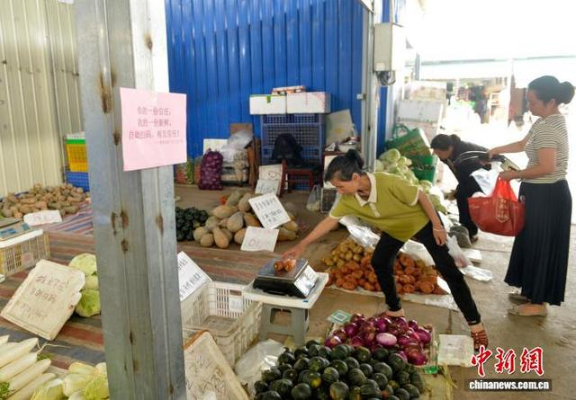 图为民众在“无人值守”蔬菜售卖摊点选购蔬菜。滕忠 摄 
