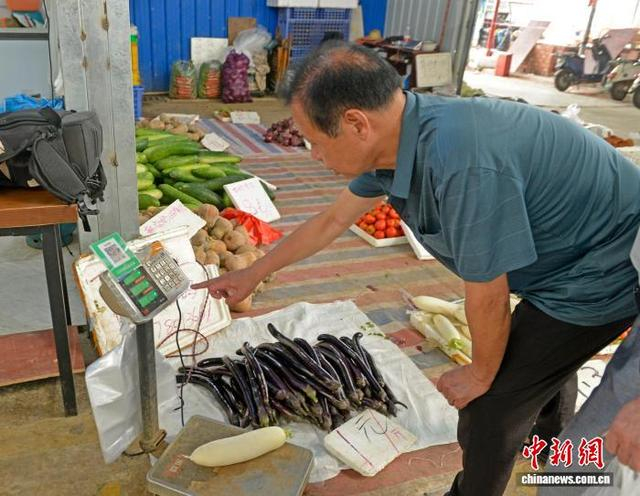 图为民众在“无人值守”蔬菜售卖摊点选购蔬菜。滕忠 摄 
