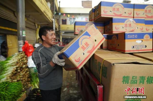 图为5月15日，工人在芒康县农贸市场搬运从云南发运过来的蔬菜。中新社记者 刘冉阳 摄