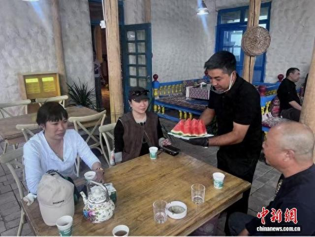 图为玉素普·艾力为客人送上本地水果。袁鹏冲 摄