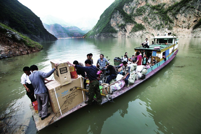 2009年秋，巴东县渡船上，三户搬家的移民与乘客挤在一起。他们带着家电、被褥，还有对新生活的期盼。 李风 图