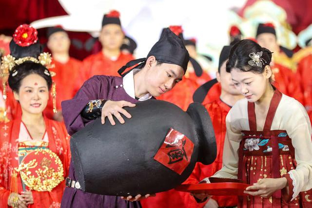 5月20日，山东青岛崂山区，集体婚礼现场，礼仪人员开坛倒酒，准备进行新人相互敬酒环节。张进刚/摄
