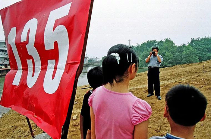 2003年6月1日，新秭归县城江边，移民们与35水位标字牌合影。李凤 图