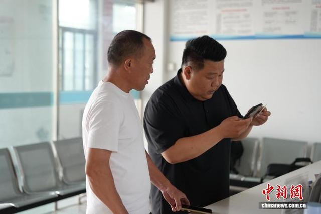 5月22日，村干部冯大吉正在帮村民缴纳养老保险。中新社记者 张俊 摄