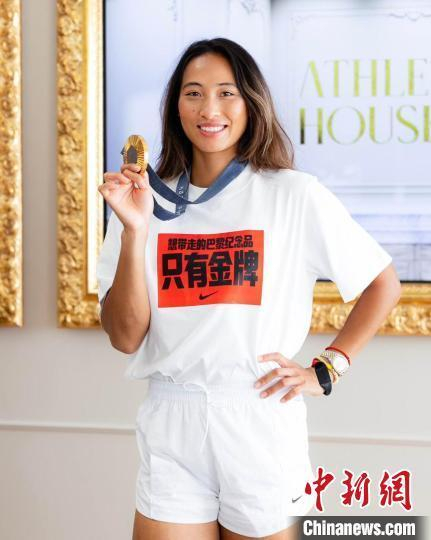 当地时间8月4日，巴黎奥运会网球女单冠军郑钦文接受记者采访，图为郑钦文在采访中展示她的金牌。中新社记者 邢翀 摄