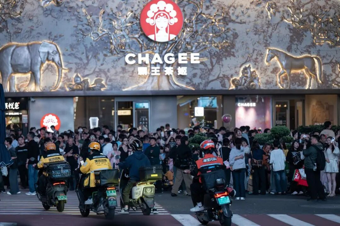 4月25日，在湖南长沙五一广场商圈，几名外卖骑手从观看大屏幕的游客旁经过。新华社记者 刘杰 摄
