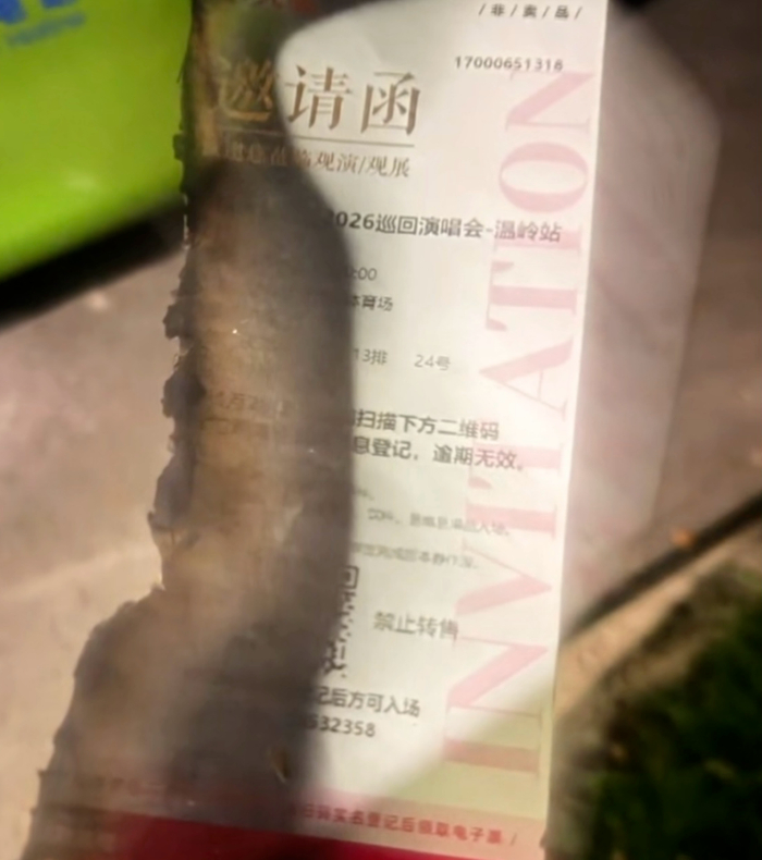 有路人捡起被烧毁的残票，所示为该演唱会的邀请函。
