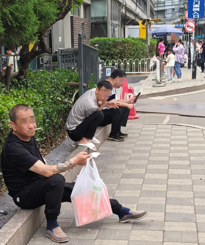 5月26日，北京某知名儿科医院大门外，数名男子在绿化带旁吸烟。该处为患儿进出必经之路。新京报记者 戴轩 摄
