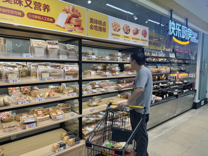 图为消费者在某商超烘焙区挑选糕点。