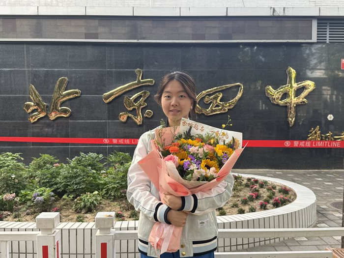 来自北京市第一五六中学的张同学手持鲜花在考点门口合影。新京报记者 徐彦琳 摄