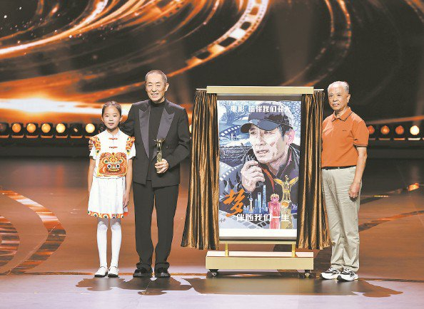             李树德（右）向张艺谋（中）赠送手绘海报  本报记者  王凯  摄          