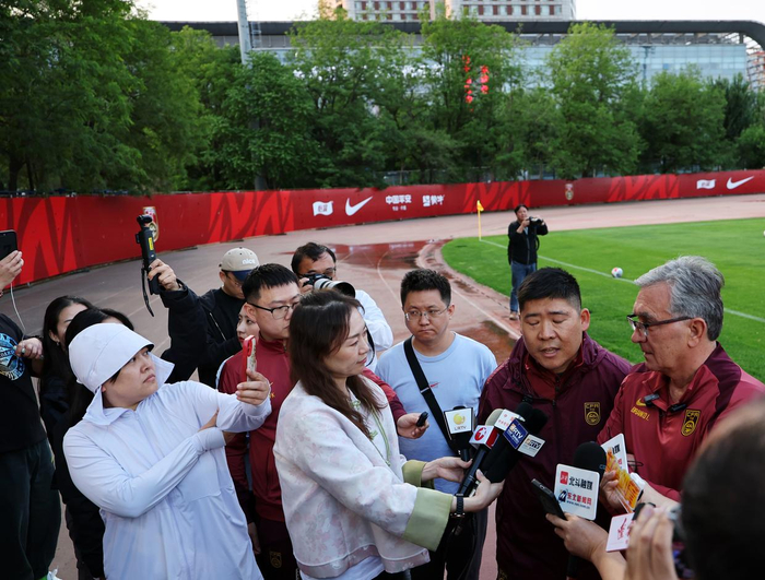 5月27日，中国队主教练伊万科维奇（右一）在训练间隙接受媒体采访。新华社记者 李钢 摄
