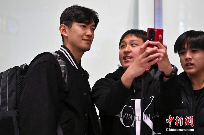图为中国男足队员颜骏凌与前来接机的球迷合影。中新社记者 赵文宇 摄
