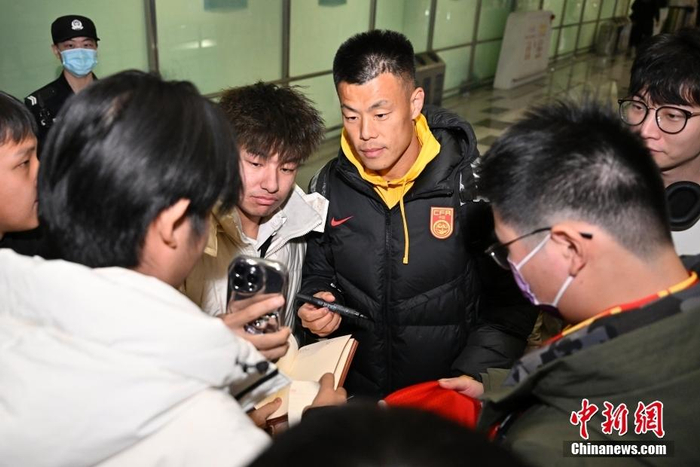 图为中国男足队员谭龙为前来接机的球迷签名。中新社记者 赵文宇 摄