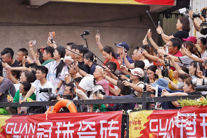 两岸观众将手机相机对准赛道。戴嘉信 摄