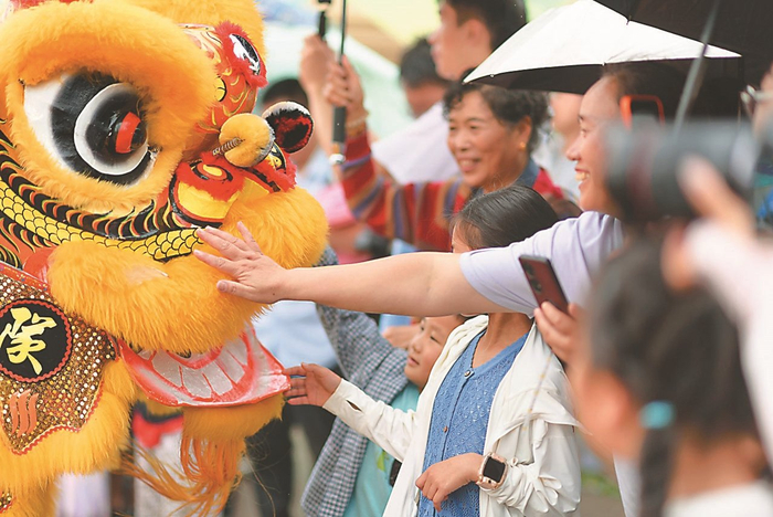  六月十九日，徐州大龙湖畔，舞狮演员与观众互动。 韩志明 摄 （视觉江苏网供图）