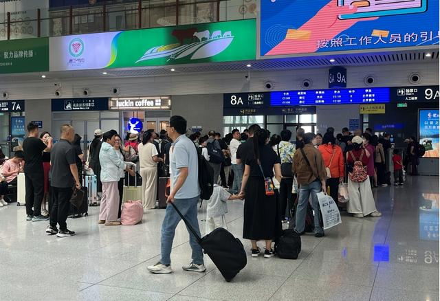 候车大厅里，旅客们在检票口排队。斯琴 摄