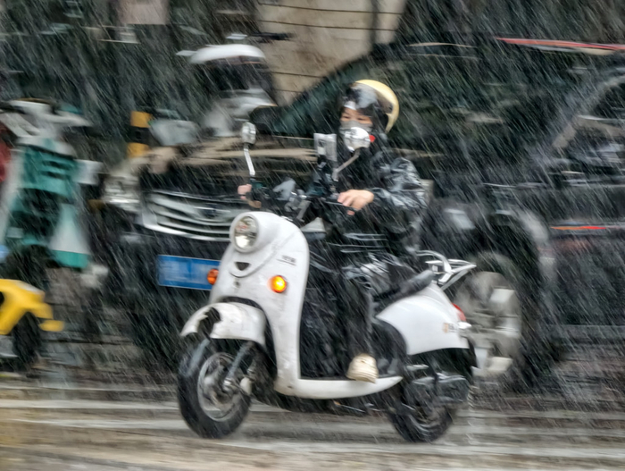 7月5日，在广西南宁市西乡塘区科德新苑路口，市民骑着电动车在风雨中出行。新华社 图