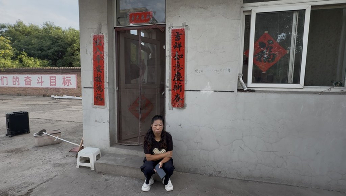 7月1日，张爱平回到曾工作过的场所，坐在门卫室门口。 本文图片均为 澎湃新闻记者 段彦超 拍摄