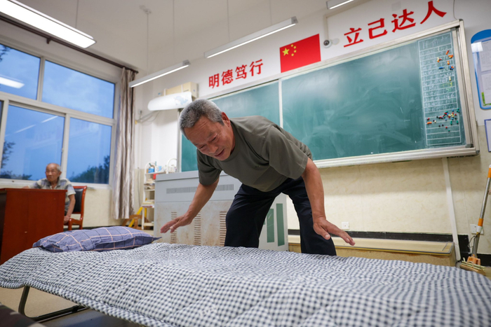 抵达学校避险的村民在教室里铺床。新京报记者 王子诚 摄