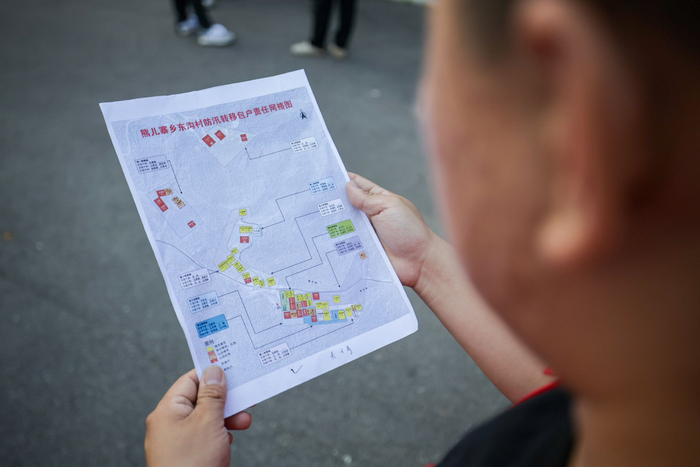 工作人员根据防汛转移包户责任网格图挨家挨户通知。新京报记者 王子诚 摄
