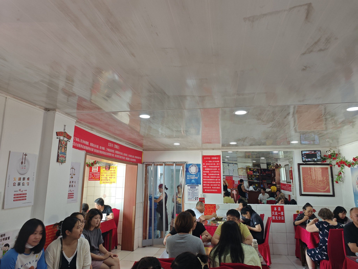 7月8日中午，饭馆里坐满了顾客，等位的人靠着墙边坐了一排。新京报记者 郭懿萌 摄