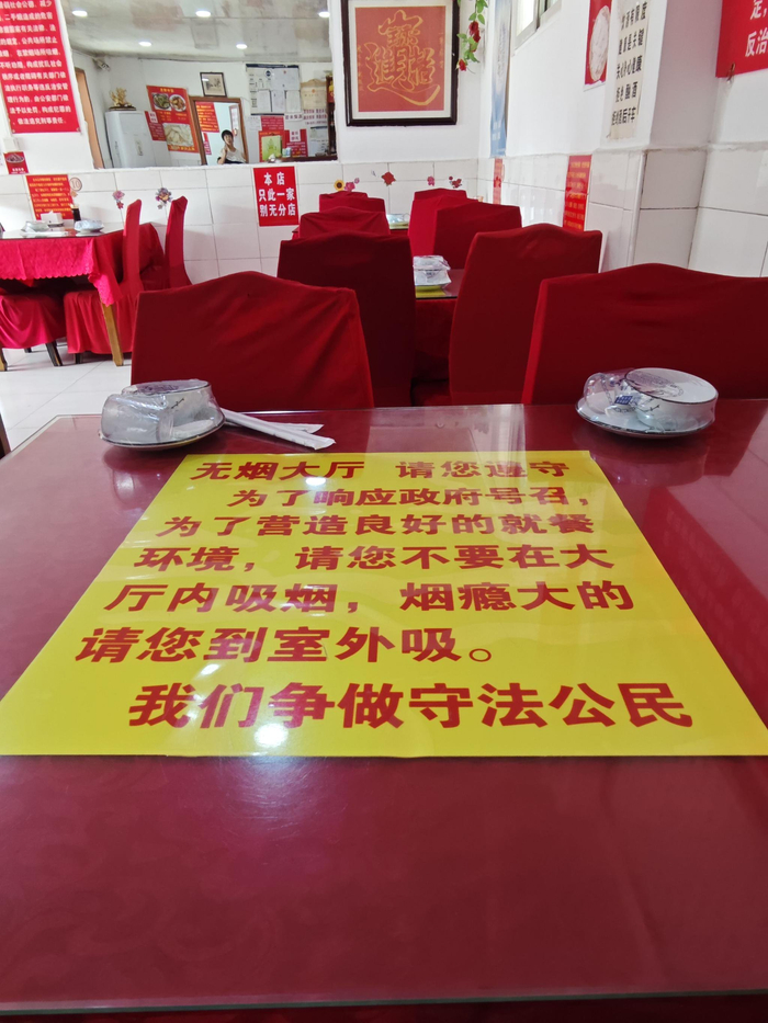 餐馆里的每张桌子都压着黄底红字的禁烟宣传语。新京报记者 郭懿萌 摄