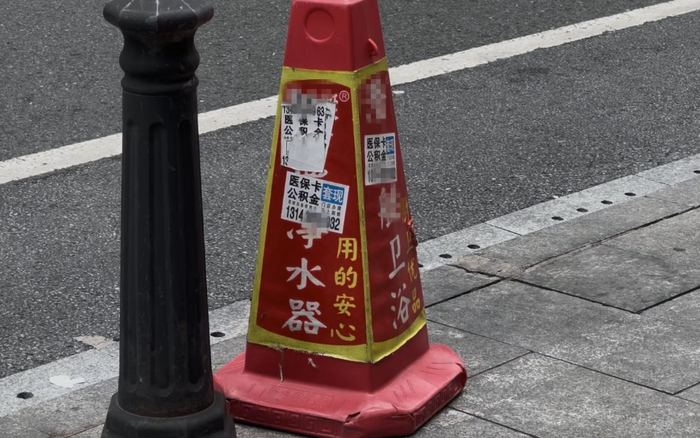 广州越秀区,路边锥桶上贴着多张医保、公积金套现的小广告。 新京报记者 齐少乾 摄
