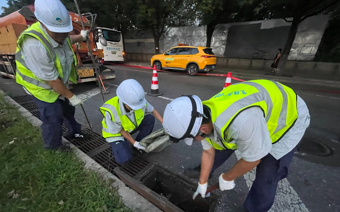8月10日晚，永定门桥一处雨水口，北京排水集团工作人员对雨水口清掏，对雨水支管进行养护。新京报记者 吴婷婷 摄