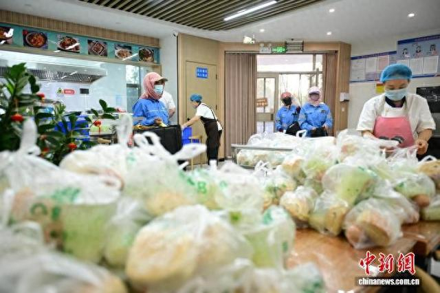 8月12日，敦煌市市直机关干部职工食堂内，工作人员为环卫工人配早餐。李亚龙 摄