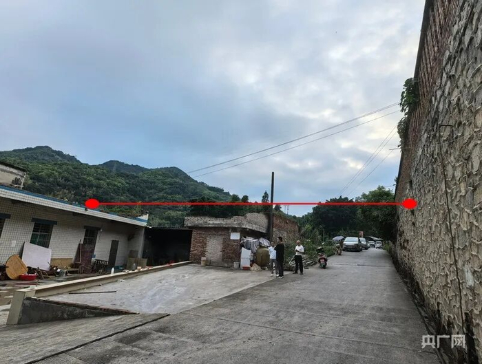 遮雨篷布横跨村道，两端分别通过房屋楼顶女儿墙与道路旁的墙体固定（央广网记者 昌思荣 摄）