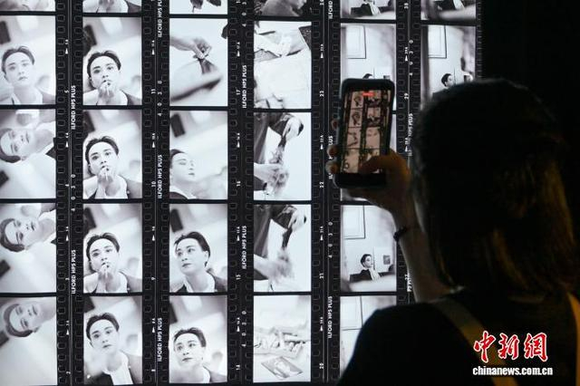图为一名女士拍摄展出的张国荣照片。中新网记者 陈永诺 摄