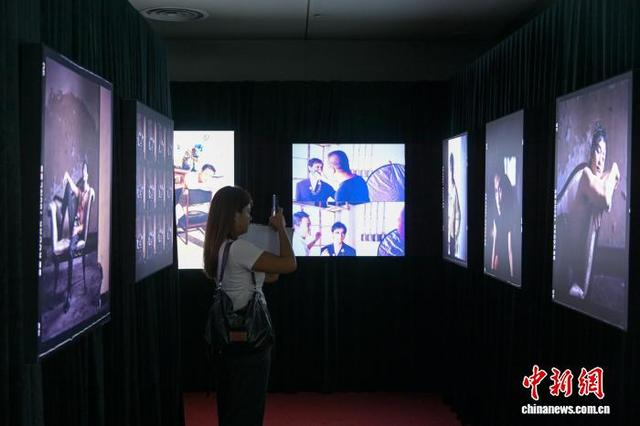 图为一名女士拍摄展出的张国荣照片。中新网记者 陈永诺 摄