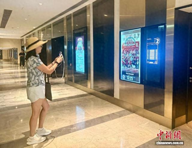 9月11日，电影《欢迎来龙餐馆》正式登陆香港、澳门院线公映。图为香港市民在影院拍摄电影宣传海报留念。中新社记者 戴小橦 摄