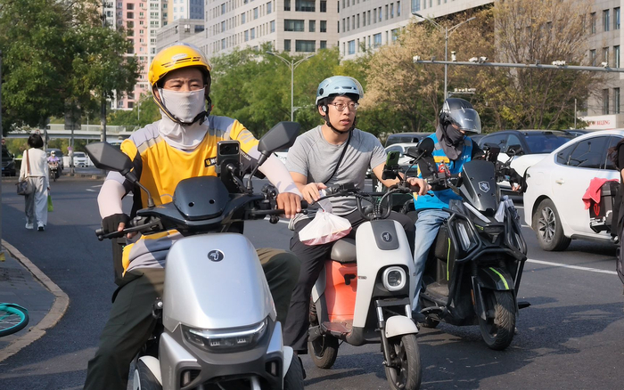 “体验官”与几名外卖骑手在一路口处等候信号灯。新京报记者 王巍 摄