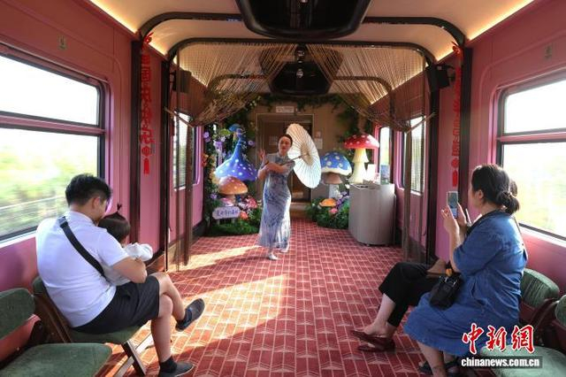 9月27日，江西上饶，旅客在“大美上饶”主题观光列车上观看车厢内的油纸伞表演。中新社记者 刘占昆 摄