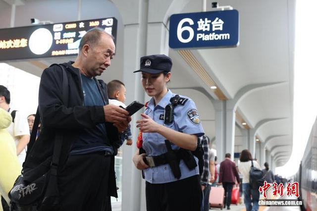图为乘警在站台上协助乘车旅客。张鑫 摄 